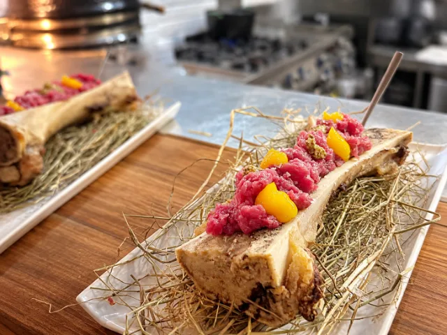 Tartare di filet mignon servita sull'osso con midollo, gel di tuorlo marinato e senape, proposta del Ristorante Ossobuco a Varese.