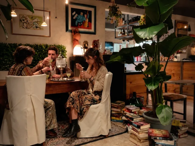 descrizione immagine Ospiti del Dai Tosi Bistrò che condividono un aperitivo in un ambiente accogliente, tra piante ornamentali, luci soffuse e dettagli d’arredo caratteristici.