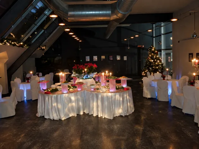 Allestimento catering del Paladino presso Altro Pianeta, con buffet centrale, tavoli apparecchiati, decorazioni natalizie e luci soffuse per un evento speciale.