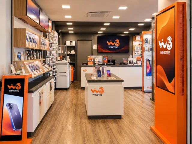 Interno del negozio WINDTRE con esposizione di smartphone e accessori, postazioni dedicate alla consulenza e arredi moderni caratterizzati dai colori del marchio.