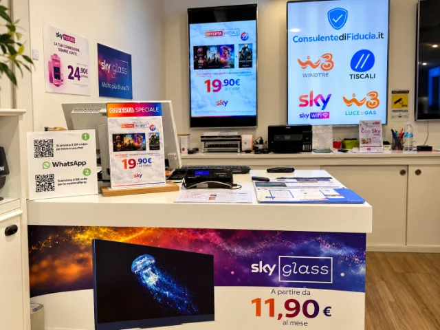 Interno del Negozio Sky Varese con banco dedicato alla consulenza e all'assistenza clienti, materiale promozionale Sky Glass e schermi informativi sulle offerte Sky.